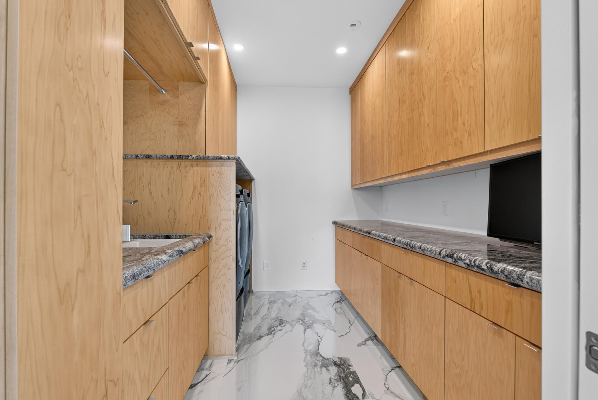 A second laundry room is conveniently located upstairs, close to the majority of the bedrooms, and finished with custom cabinetry, generous counterspace, sink, LG washer and dryer, and motion-activated lighting.