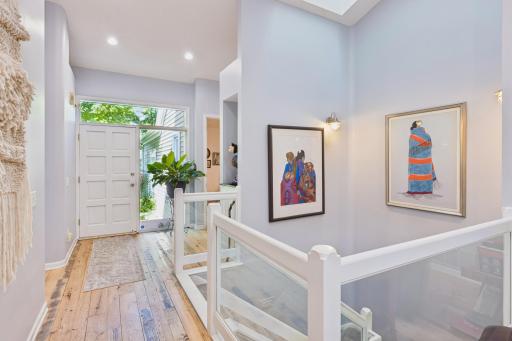 Elegant glass railing and gleaming hardwood floors add a modern touch to this level.