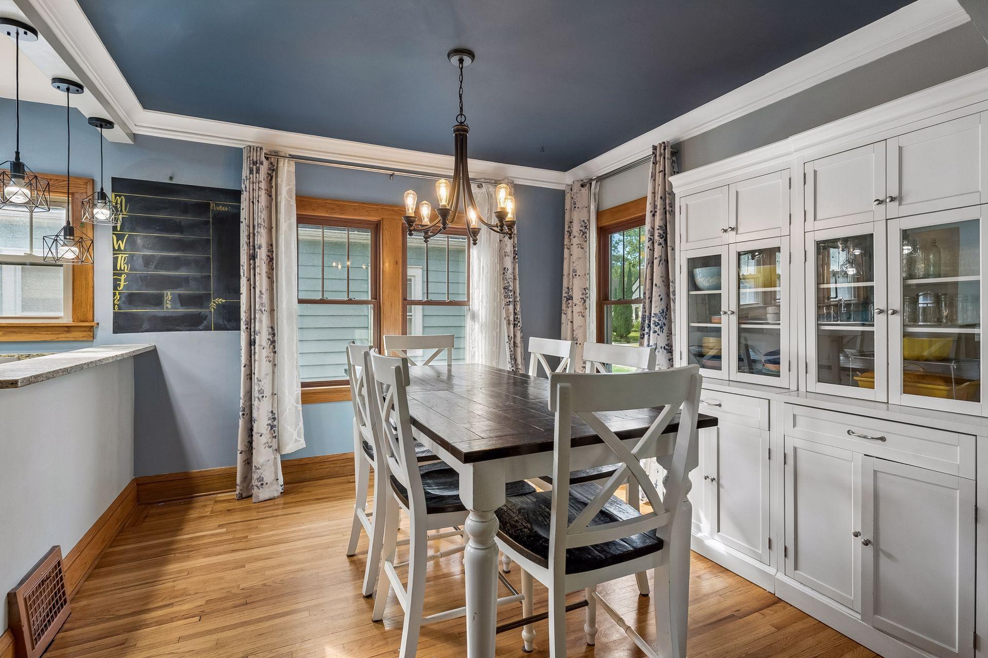 The dining room has room for a full table, a statement chandelier, and a dramatic painted ceiling with crown molding. Windows on two sides keep it bright all day.