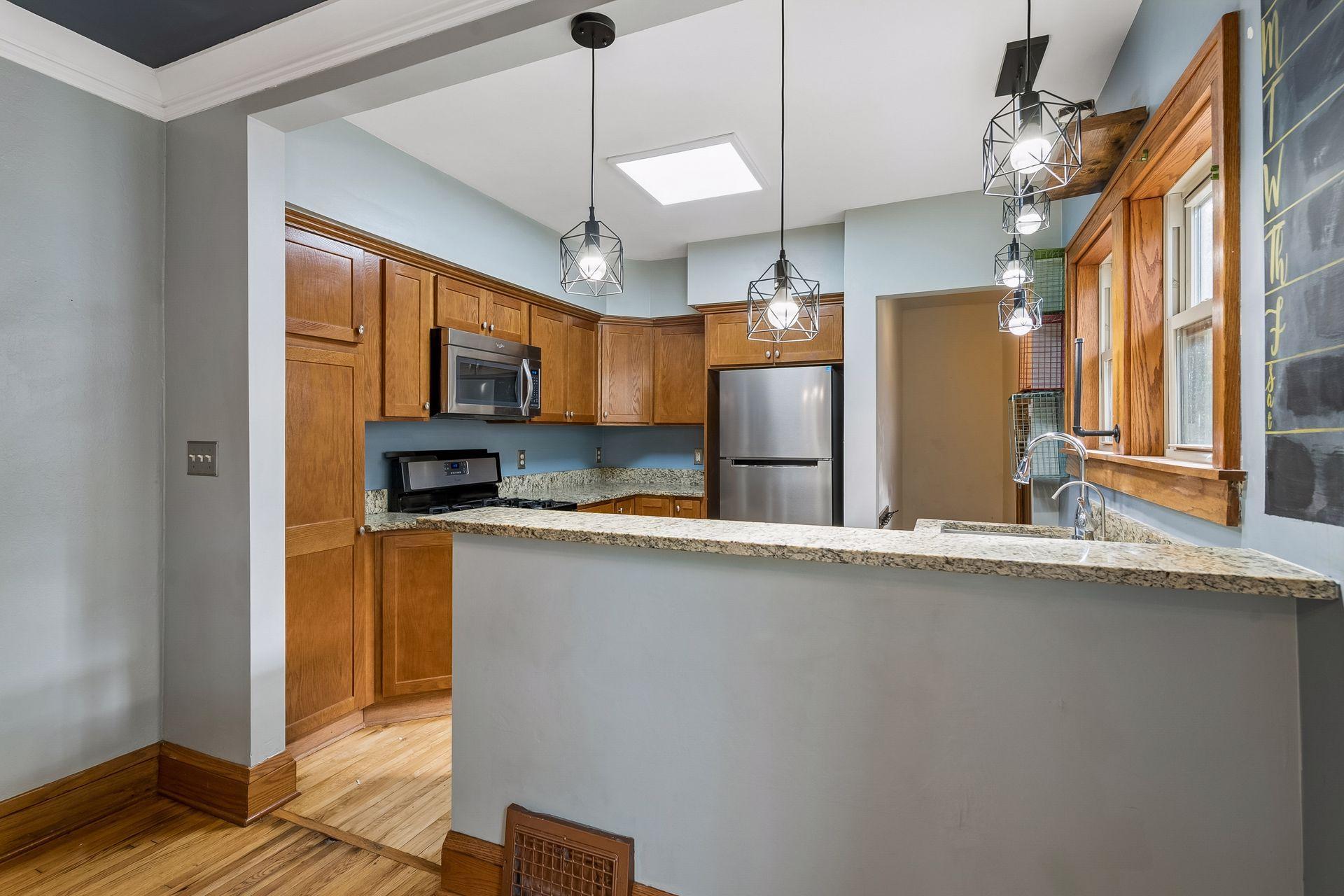 The kitchen opens to the dining room over a granite breakfast bar, a natural spot for quick meals and morning coffee. Modern pendant lights add a stylish touch.