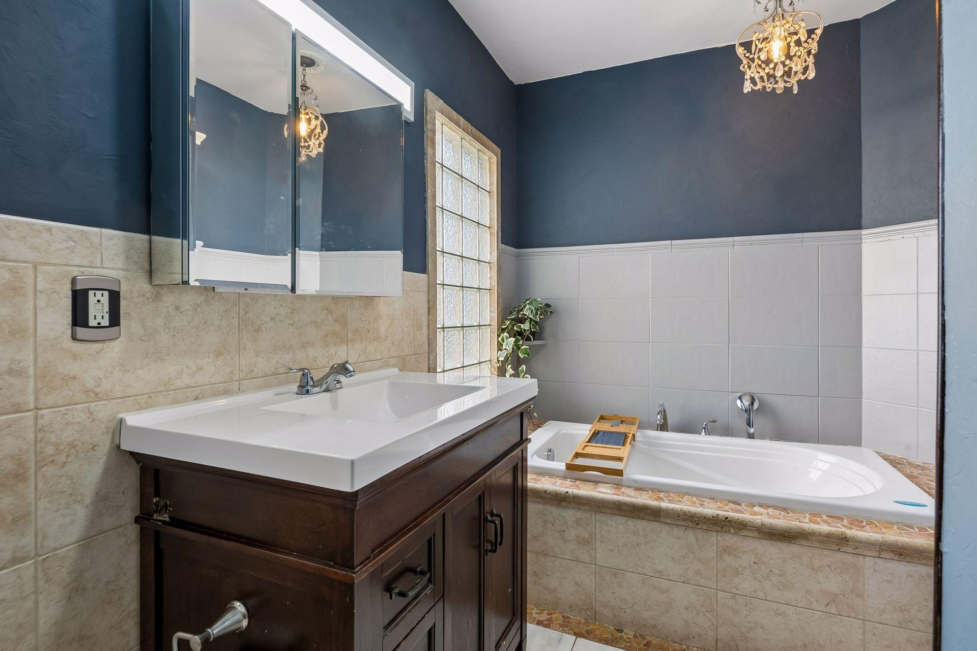The main level bath feels like a retreat, with heated floors, a jetted tub, and a sparkling crystal light fixture. Glass block windows let in natural light while keeping things private.