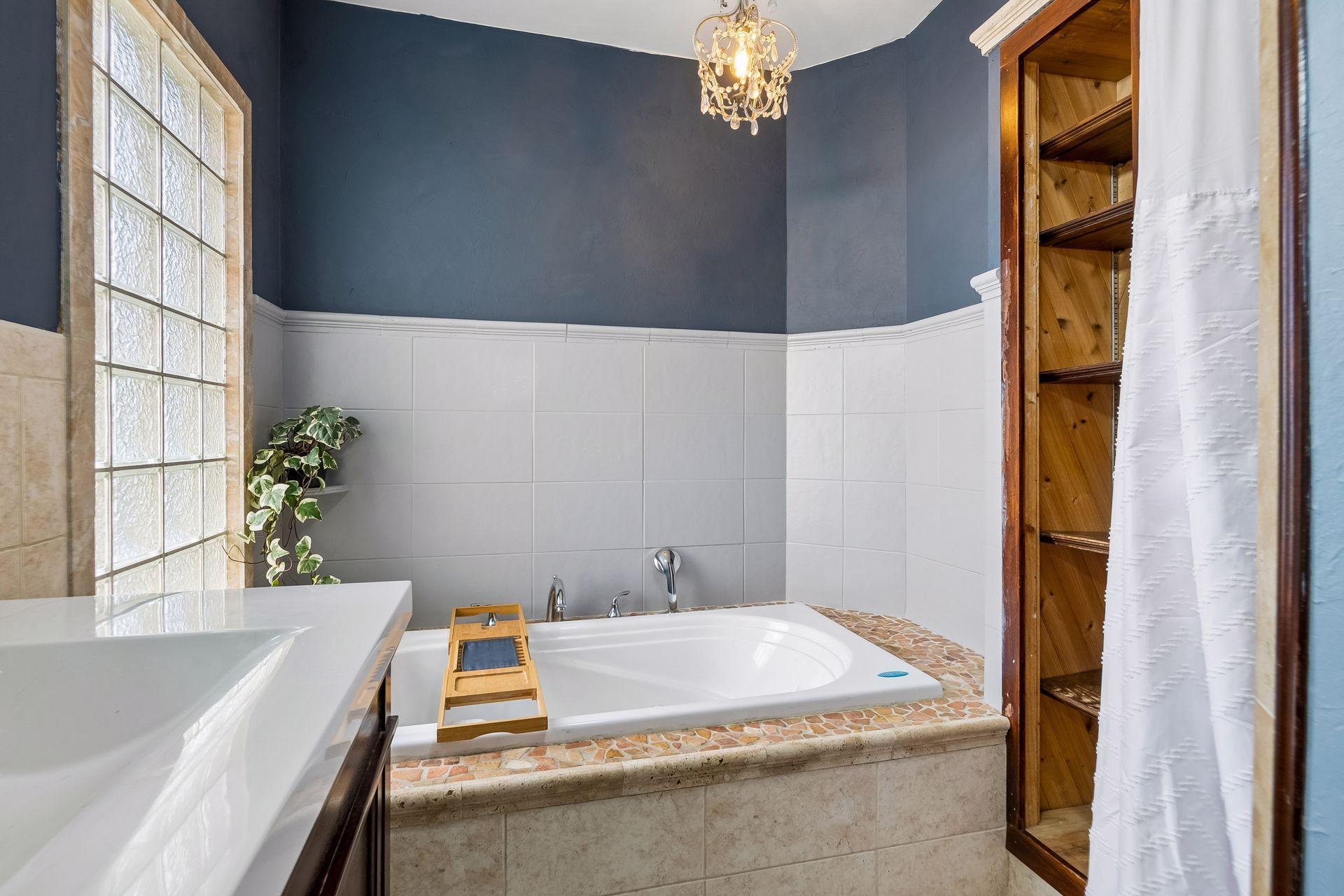 Unwind in the jetted tub, with freshly cleaned jets and a stone mosaic surround. Built-in wood shelving next to the tub keeps towels and essentials close at hand.