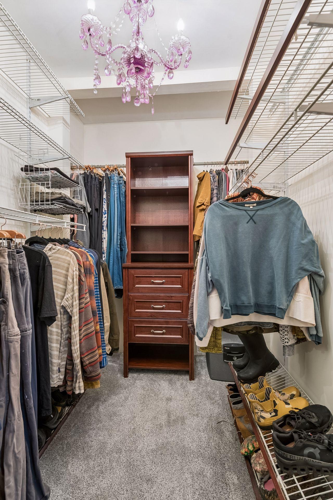 The primary bedroom includes a generous walk-in closet with wire shelving, double hanging rods, and a built-in drawer tower to keep everything organized.