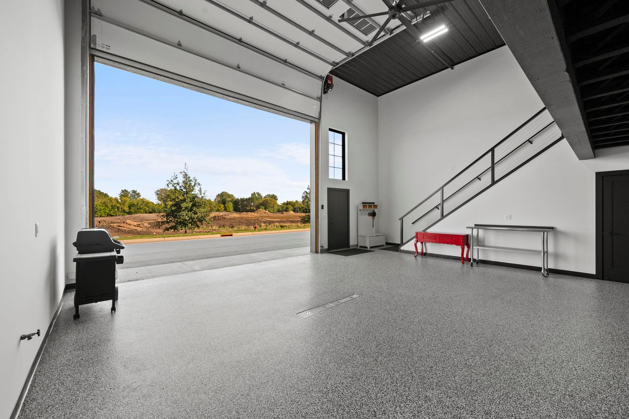 The impressive 30’ x 40’ main-level high-bay area features 20’ ceilings, a fully insulated wood-look garage door with myQ-compatible operator, Pella windows, acoustical black metal ceiling, Wi-Fi-controlled in-floor heat, split AC, and a large fan.