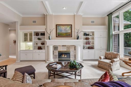 Inviting great room features a gas fireplace surrounded by custom built-ins and walls of windows overlooking the backyard.