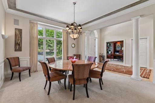 Formal dining room with detailed millwork, tray ceiling, built-in buffet and oversized windows.