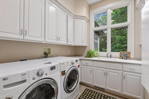 Main-level laundry room offers a utility sink, extensive cabinetry, counter space and natural light. Mud room off garage with large closet and built-in storage and bench.