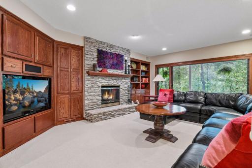 Cozy family room with stone fireplace, custom built-ins and large windows overlooking the backyard.