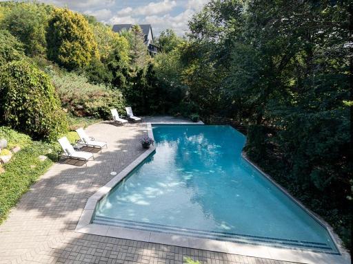 Private backyard retreat with an in-ground infinity-edge pool, expansive paver patio and lush mature landscaping.