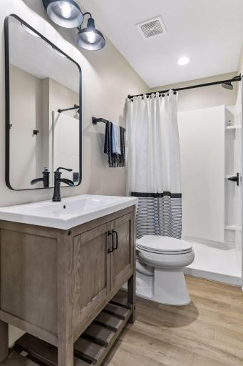 Stylish lower-level bath features a modern vanity, updated fixtures, and a convenient walk-in shower. Perfect for guests and everyday use, this thoughtfully finished space adds comfort and functionality to the lower-level living area.