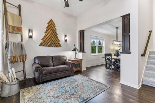 Warm and inviting, this beautifully designed living space features rich wood-look flooring, abundant natural light, and an open-concept layout perfect for everyday living and entertaining. A cozy seating area is highlighted by stylish wall sconces