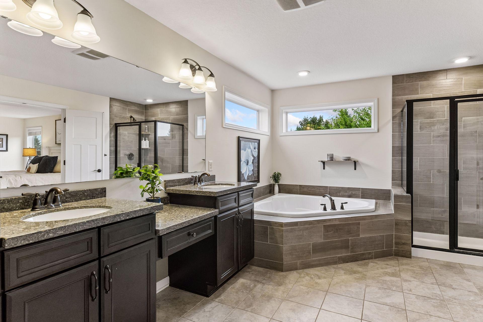 Luxurious primary bath features dual vanities, a relaxing soaking tub, separate shower, and elegant finishes. The spacious walk-in closet offers exceptional storage, creating a private retreat designed for comfort and convenience.