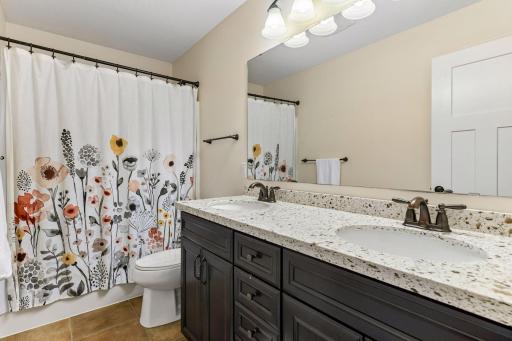 Full upper-level bath features a dual-sink vanity, generous counter space, and a tub/shower combination. Thoughtfully designed to accommodate busy mornings, this stylish and functional bath comfortably serves the secondary bedrooms.