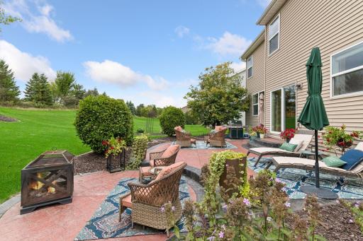 Enjoy your own backyard retreat! Expansive stamped concrete patio offers multiple seating areas, lush landscaping, and scenic green space views. Perfect for entertaining, relaxing by the fire, or enjoying quiet evenings outdoors.