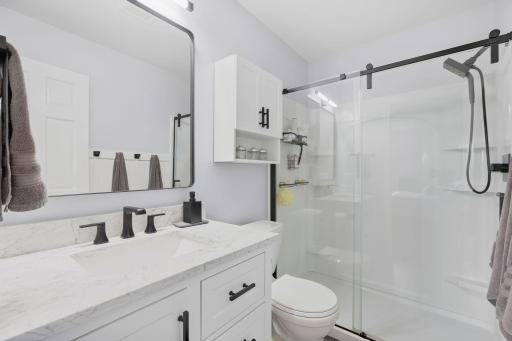 Custom primary bathroom with marble counter, glass sliding shower door.