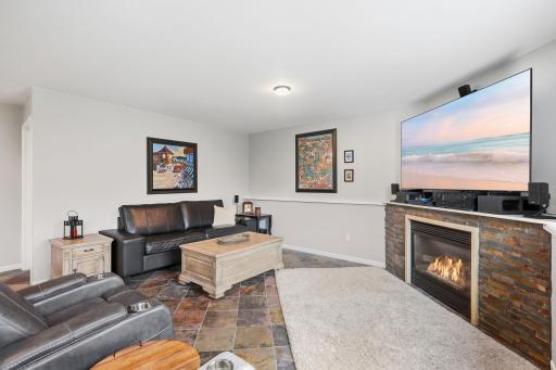 Lower level family room with custom tile flooring, amazing stone gas fireplace surround, included 75" flat screen TV, light & bright sun filled room.