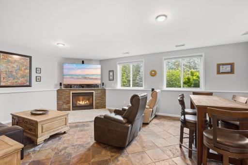 Lower level family room with custom tile flooring, amazing stone gas fireplace surround, included 75" flat screen TV, light & bright sun filled room.