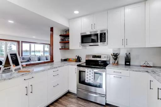 Bright kitchen features crisp white cabinetry, stainless steel appliances, and abundant storage.