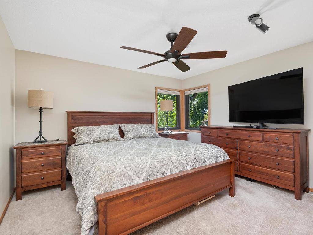 Main-level bedroom with corner windows and a ceiling fan.