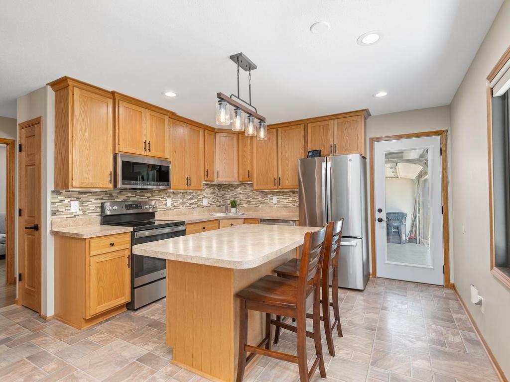 The kitchen features a seating island, stainless-steel appliances, and ample cabinet space.