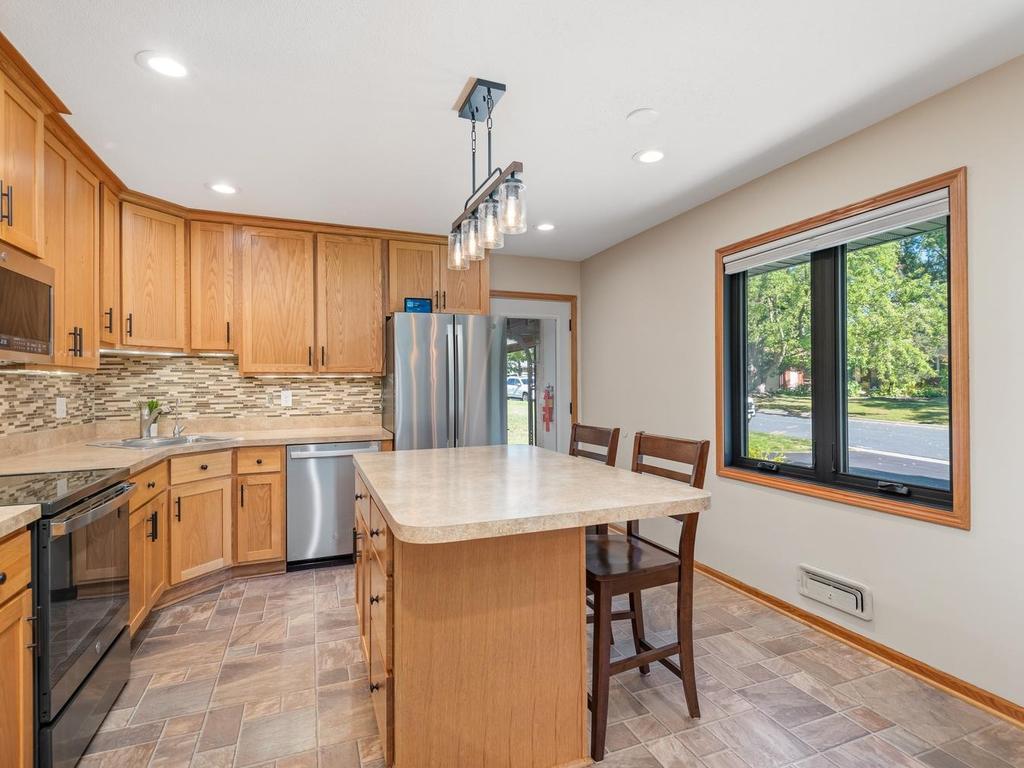 A large window brings natural light into the kitchen and island seating area.