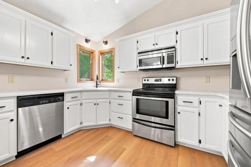 Kitchen features new lighting, freshly painted cabinets, and new quartz countertops.