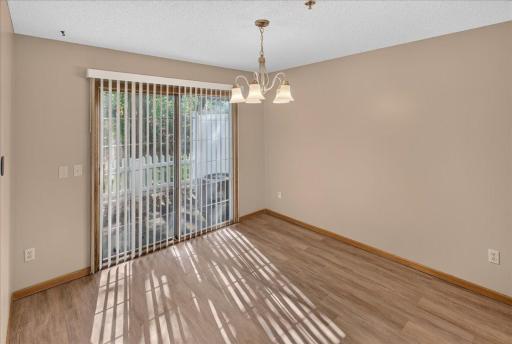 Dining area with new LVP flooring, fresh neutral paint and sliding-door access to the private patio.
