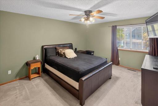 Generously sized primary bedroom with a large window and ceiling fan.
