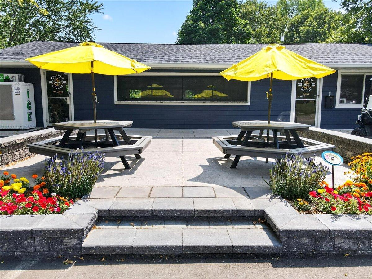 Inviting outdoor patio area features picnic tables, colorful landscaping, and convenient access to the lodge.