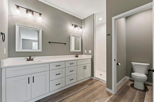 Gorgeous primary bath with double sinks, walk-in tiled shower, and a separate toilet room