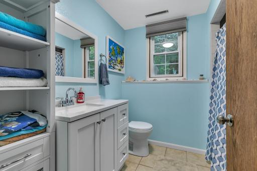 A three-quarter bathroom features tiled flooring, a tiled shower surround, and an updated vanity and toilet.