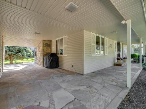 Covered wrap around foyer with flagstone patio compliments the exterior stone work on home and chimneys.