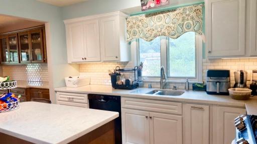 Crisp white kitchen with charming café style valance. Cooking here just feels good.