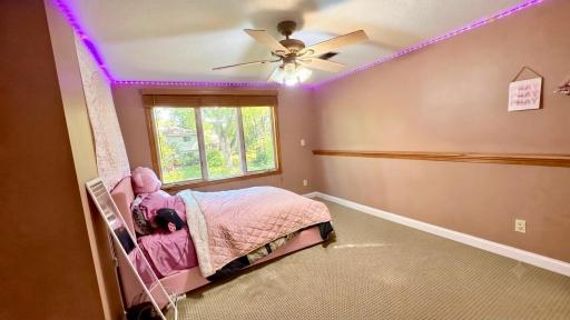 Charming bedroom with ceiling fan and a peaceful wooded view.