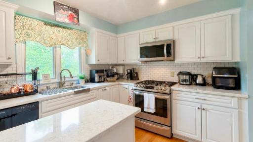 Gleaming white kitchen with quartz counters and stainless range. A dream for any home chef.