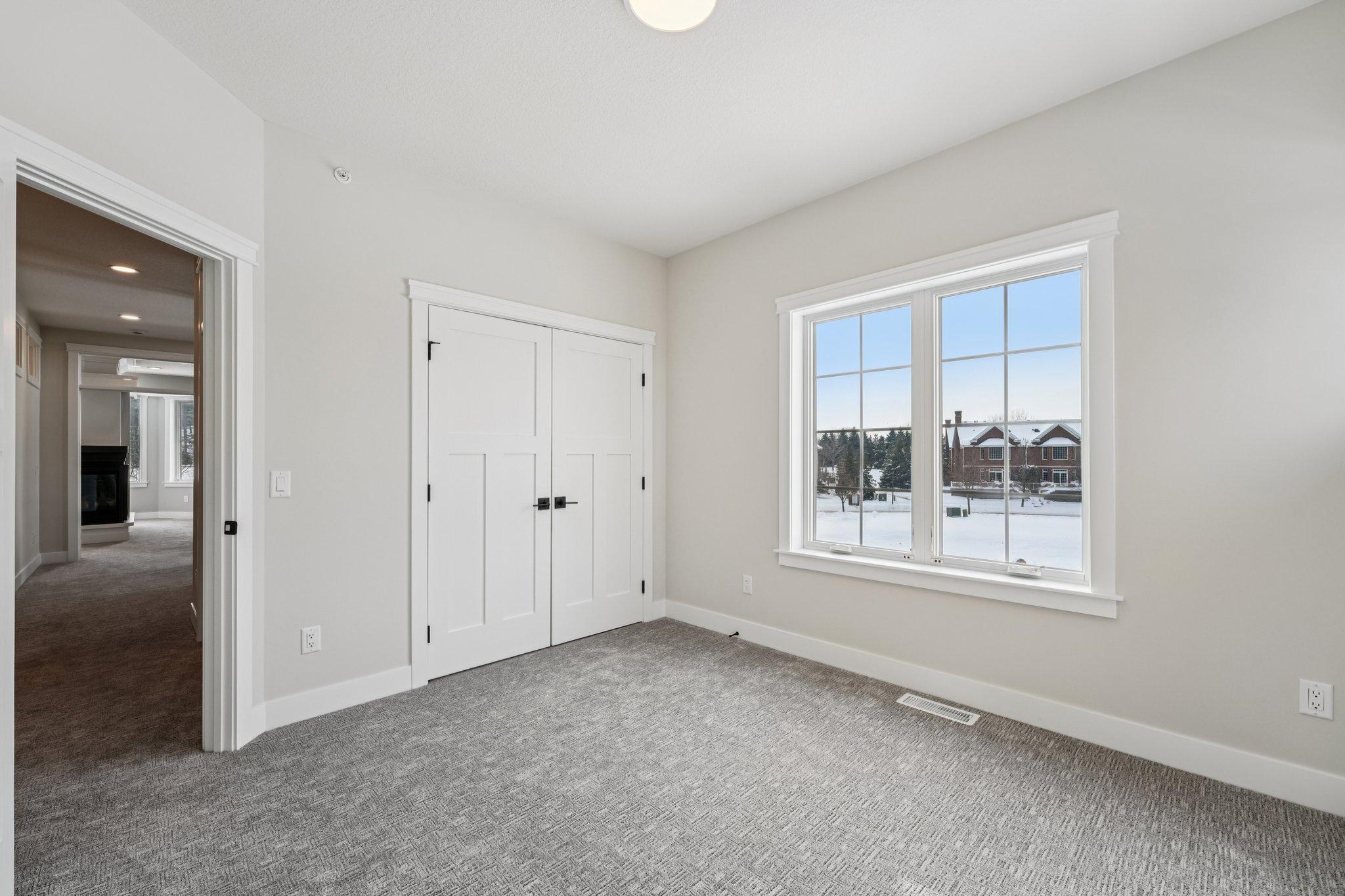 Well-proportioned bedroom showcasing generous natural light, double closet doors, and clean modern finishes.