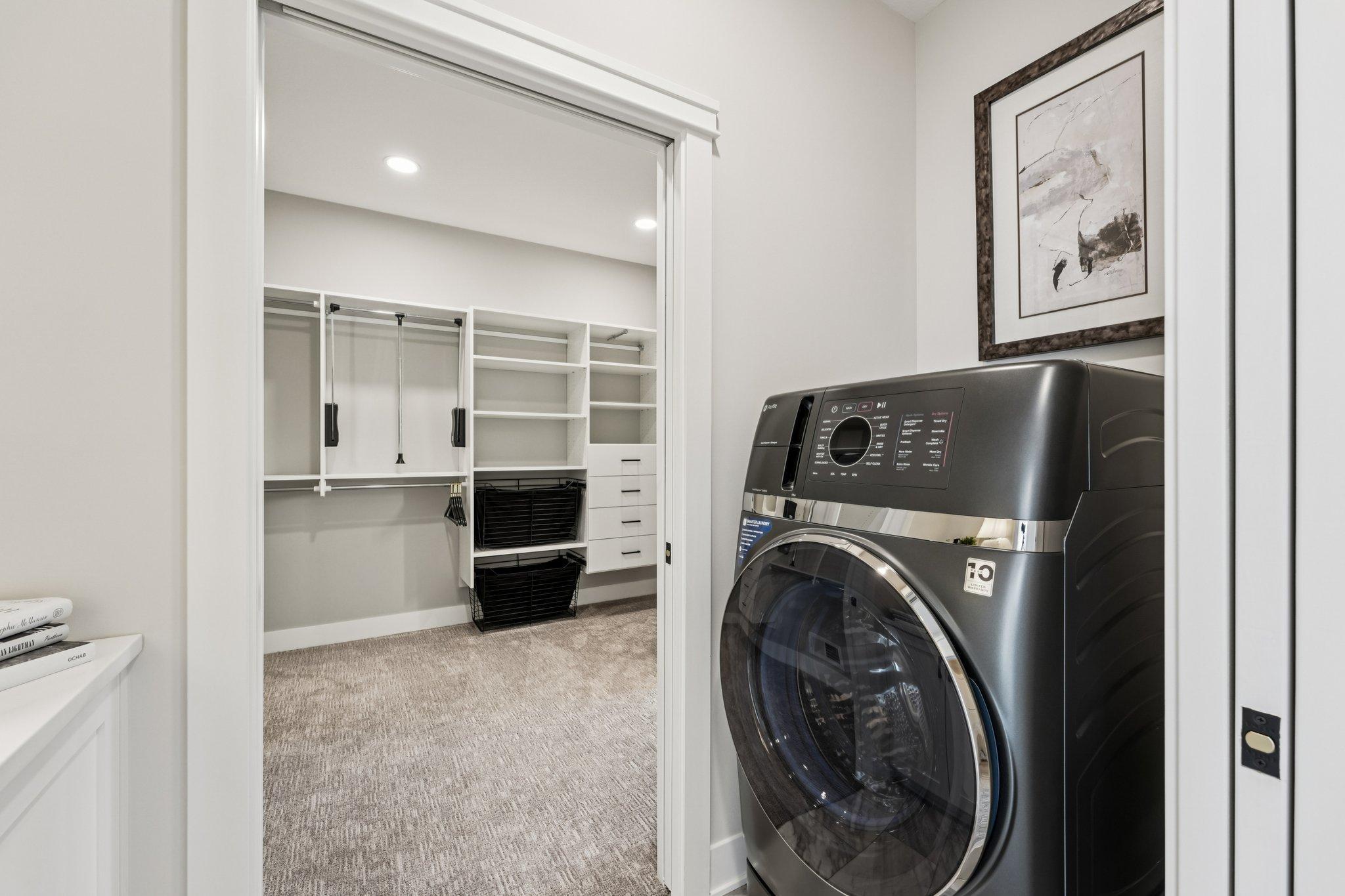 Convenient laundry room with front-load washer and dryer, adjacent to a spacious walk-in closet with custom shelving and organization.