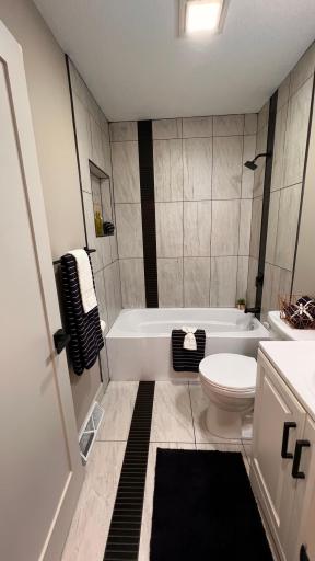 Main level full bath with beautiful tile feature wall and floor