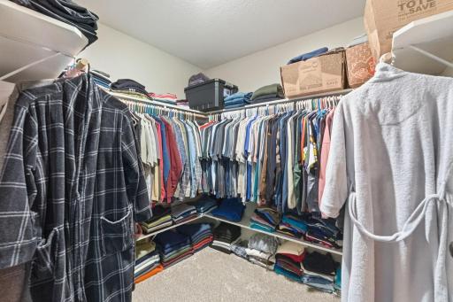 A massive, four-sided walk-in closet fully loaded with hanging rods and built-in shelving on every single wall.