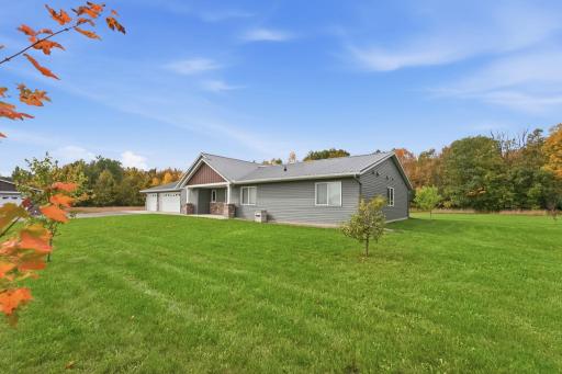 New trees and a perfectly manicured lawn create a picturesque yard, beautifully bridging the comfort of home with the natural splendor of the surrounding woods.