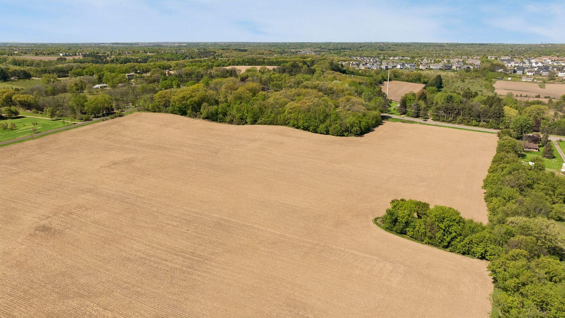 Gently rolling terrain unfolds into a picturesque landscape framed by mature trees, open meadows, and serene natural beauty in every direction.