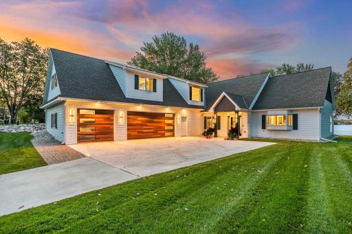 Custom architectural lighting illuminates the home's facade, creating a warm and welcoming morning ambiance.