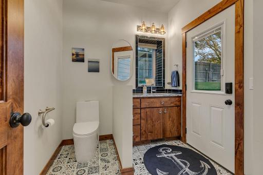 Thoughtfully designed, multi-functional 1/2 bath with custom cabinets, tiled garden window above sink, exterior door leads to lakeside patio.