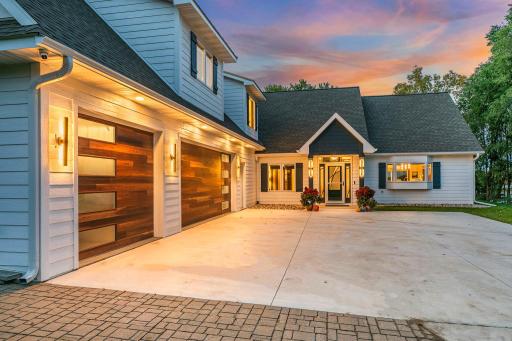 Distinctive lighting illuminates the home's facade, a charming front porch welcomes guests into the heart of the home.
