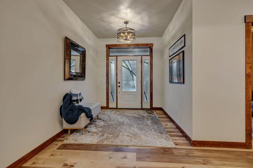Spacious sun filled foyer with distinctive glass door and sidelights plus decorative chandelier.