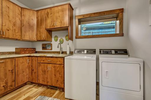 Main floor laundry has functional layout with dedicated wash sink, granite counters, Speed Queen washer & dryer.