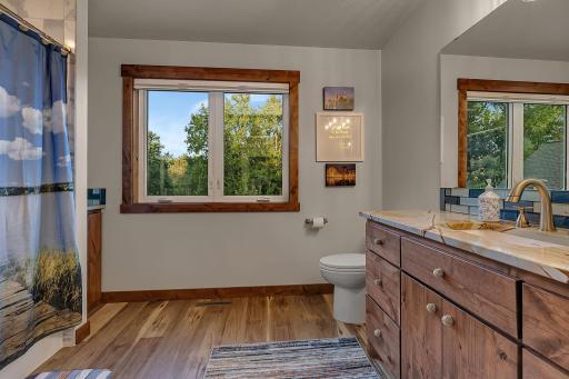 Upper level full bath, custom cabinets, nautical knot pulls, granite counter, glass tile below mirror.