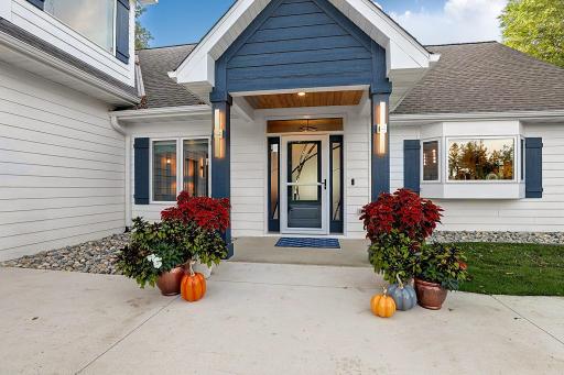 Welcoming front porch with stunning light fixtures and modern distinctive glass door with matching side lights.
