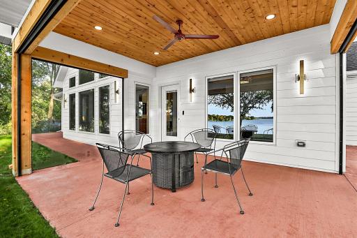 Patio without the screen down featuring a dramatic, rich natural wood paneled ceiling accented by a sleek contemporary ceiling fan and architectural post columns.