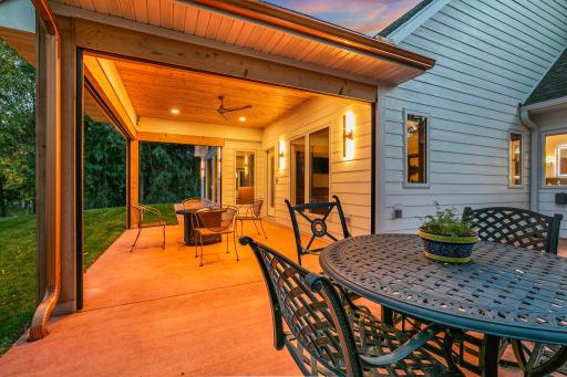 Elegant exterior sconces frame the multi-view windows and glass door entry, illuminating the expansive colored concrete flooring.